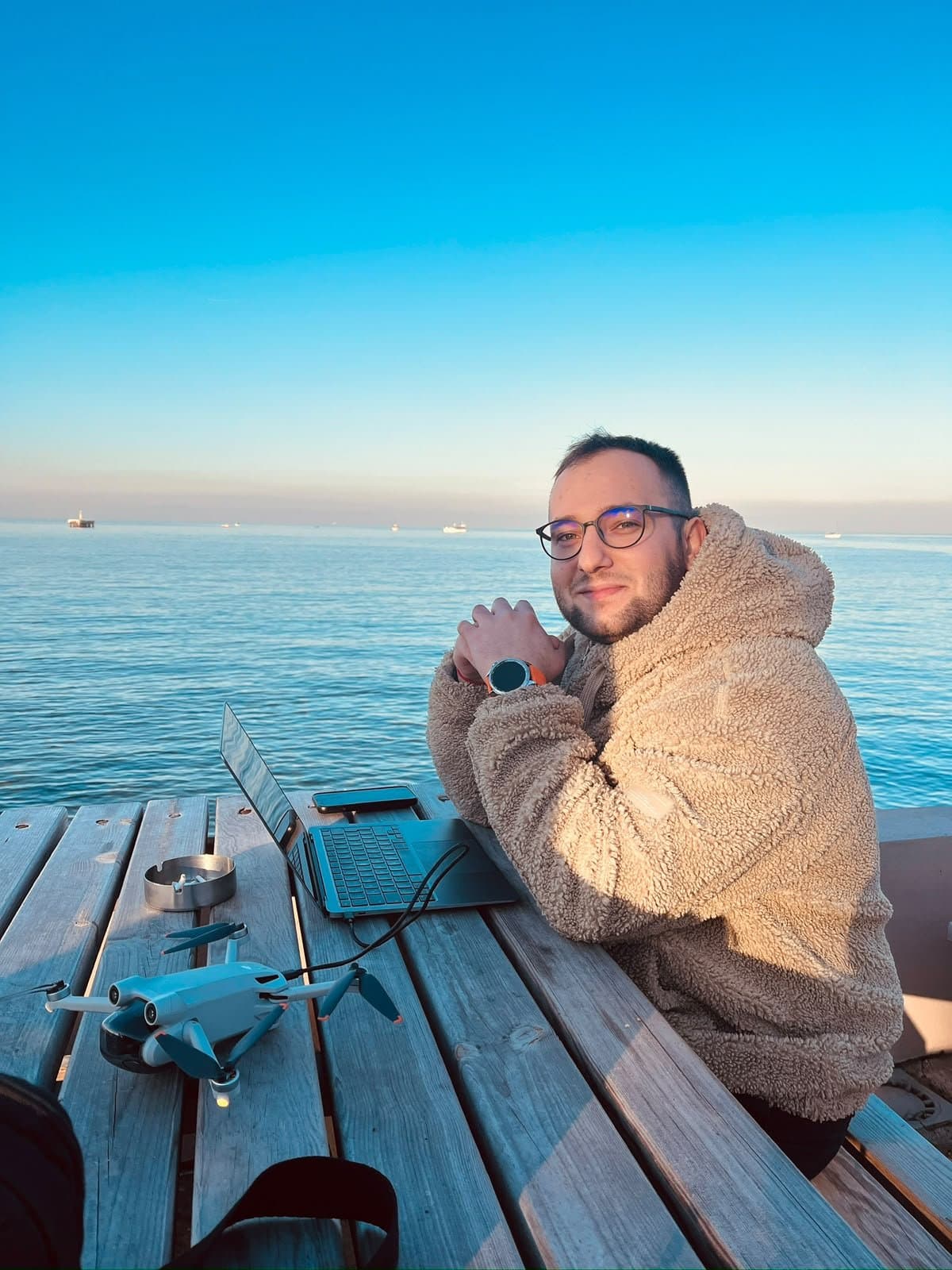 Tuğra, deniz kenarında dizüstü bilgisayarı ve drone'uyla çalışırken