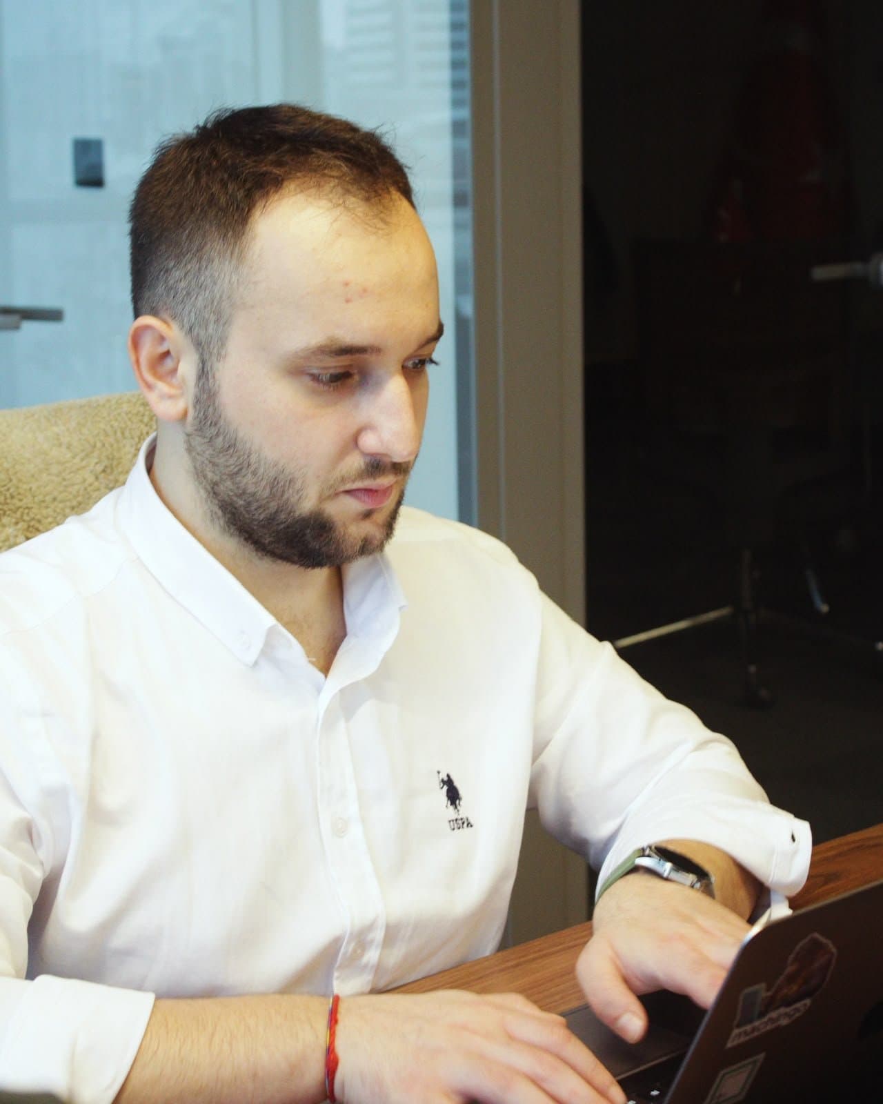 Tuğra, ofiste dizüstü bilgisayarında çalışırken